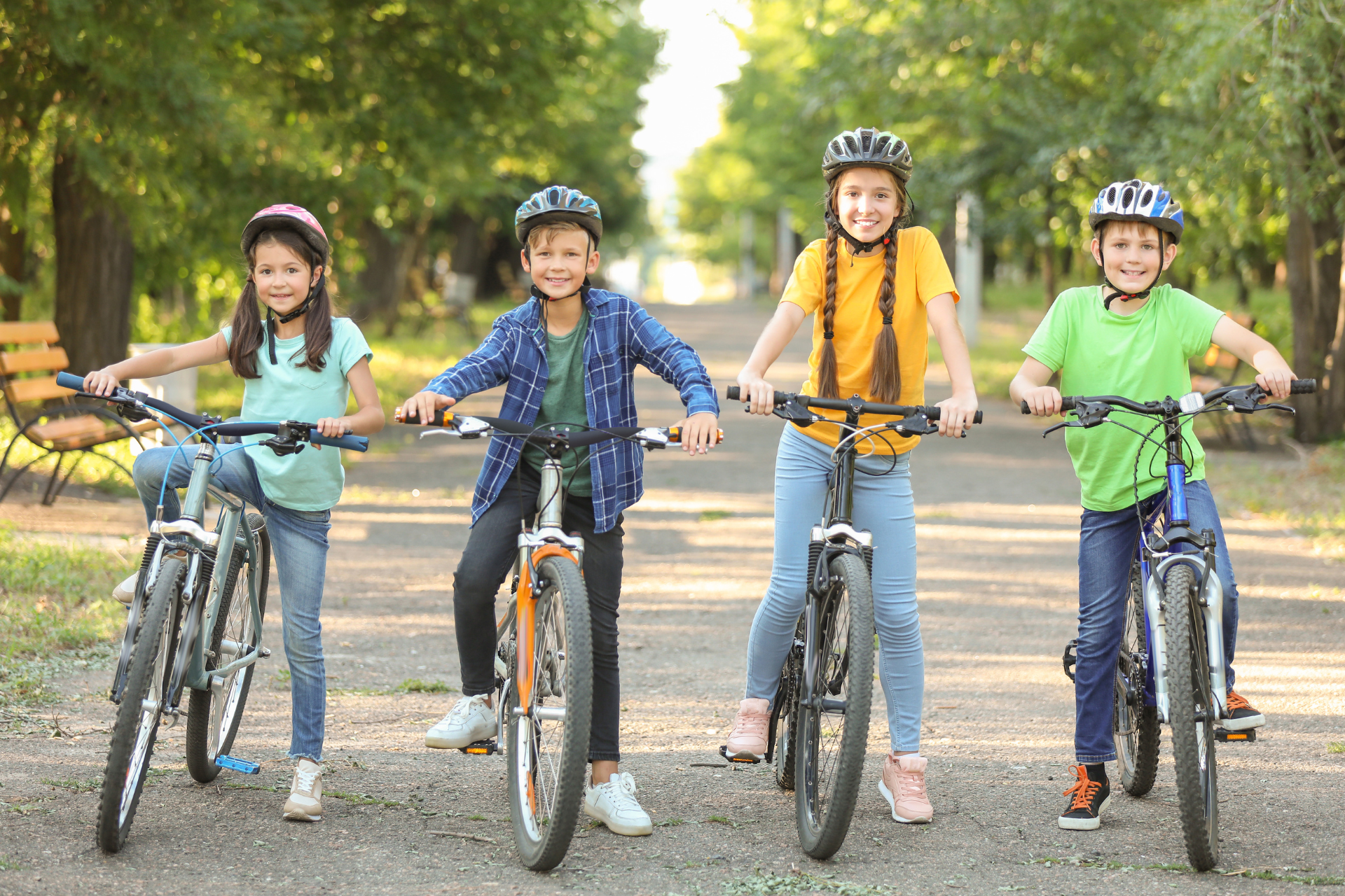 4 kids on bikes on a road with trees in the background